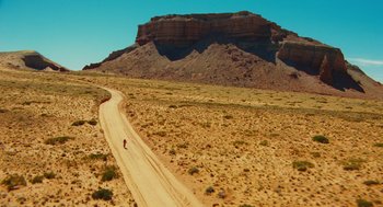 Movie still from “127 Hours” (2010), directed by Danny Boyle – A person riding a bike down a dirt road in the desert; Extreme Wide shot, High angle