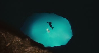 Movie still from “127 Hours” (2010), directed by Danny Boyle – A person swimming in a body of water at night; Extreme Wide shot, Overhead angle