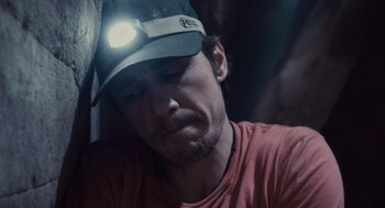 Movie still from “127 Hours” (2010), directed by Danny Boyle – A person wearing a hat with a headlight on; Close Up shot, High angle