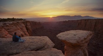 Movie still from “127 Hours” (2010), directed by Danny Boyle – The sun is setting over a canyon in the desert; Extreme Wide shot, High angle