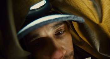 Movie still from “127 Hours” (2010), directed by Danny Boyle – A man's face wearing a hat and holding a flashlight; Extreme Close Up shot, Overhead angle