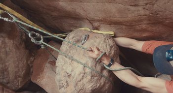 Movie still from “127 Hours” (2010), directed by Danny Boyle – A person is holding onto a rope while climbing a rock wall; Medium shot, Low angle