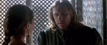 A man with long blonde hair is looking at a woman