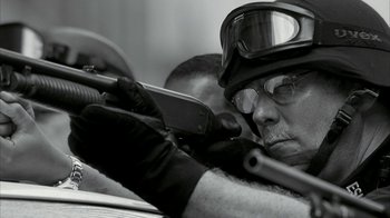 Movie still from “16 Blocks” (2006), directed by Richard Donner – A man wearing a helmet and gloves holding a rifle; Close Up shot, Over the shoulder angle