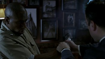 Movie still from “16 Blocks” (2006), directed by Richard Donner – A man in a suit and tie holding a remote control; Medium shot, Over the shoulder angle