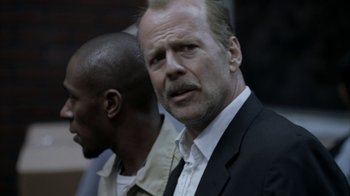 Movie still from “16 Blocks” (2006), directed by Richard Donner – A man in a suit and tie standing next to another man; Close Up shot, Over the shoulder angle