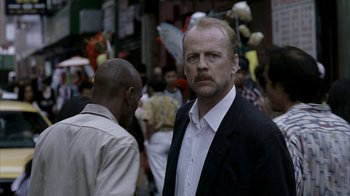 Movie still from “16 Blocks” (2006), directed by Richard Donner – A person wearing a suit on a city street; Close Up shot, Over the shoulder angle