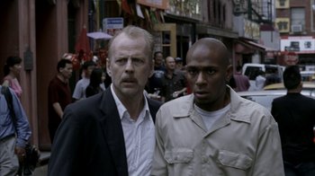 Movie still from “16 Blocks” (2006), directed by Richard Donner – Two men standing next to each other on the street; Close Up shot, Over the shoulder angle