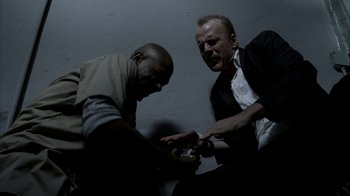 Movie still from “16 Blocks” (2006), directed by Richard Donner – Two men sitting next to each other in a dark room; Medium shot, Low angle