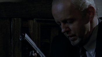 Movie still from “16 Blocks” (2006), directed by Richard Donner – A man holding a gun while looking down at it; Close Up shot, Low angle