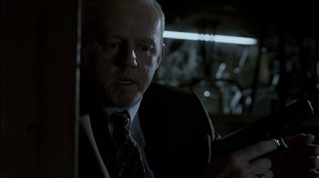 Movie still from “16 Blocks” (2006), directed by Richard Donner – A man in a suit and tie holding a guitar; Close Up shot, Over the shoulder angle