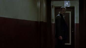 Movie still from “16 Blocks” (2006), directed by Richard Donner – A man in a suit standing next to a door; Medium shot, Over the shoulder angle