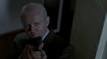 Movie still from “16 Blocks” (2006), directed by Richard Donner – A man in a suit and tie holding a gun; Close Up shot, Low angle
