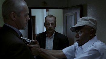 Movie still from “16 Blocks” (2006), directed by Richard Donner – A group of men standing in front of each other in a room; Medium shot, Over the shoulder angle
