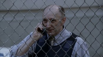 Movie still from “16 Blocks” (2006), directed by Richard Donner – A man in a vest and tie talking on a cell phone; Medium shot, High angle