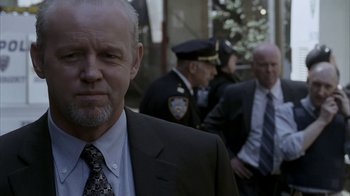 Movie still from “16 Blocks” (2006), directed by Richard Donner – A man in a suit and tie standing next to other men in suits; Close Up shot, Over the shoulder angle