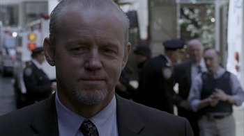 Movie still from “16 Blocks” (2006), directed by Richard Donner – A man in a suit and tie standing in front of a crowd; Close Up shot, Over the shoulder angle