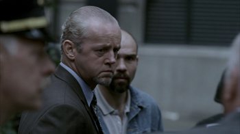 Movie still from “16 Blocks” (2006), directed by Richard Donner – A man in a suit standing next to another man in a jacket; Close Up shot, Over the shoulder angle