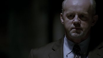 Movie still from “16 Blocks” (2006), directed by Richard Donner – A man wearing a suit and tie in a dark room; Close Up shot, Over the shoulder angle