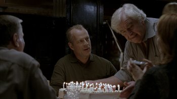Movie still from “16 Blocks” (2006), directed by Richard Donner – A group of people sitting around a table with a cake; Medium shot, Over the shoulder angle