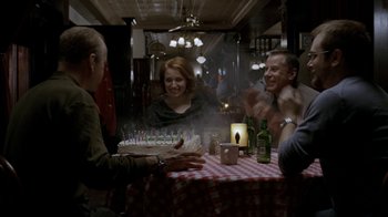 Movie still from “16 Blocks” (2006), directed by Richard Donner – A group of people sitting around a table with a cake; Medium shot, Over the shoulder angle