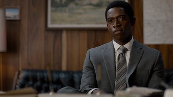 Movie still from “Snowfall” (2017), directed by Hiro Murai – A man in a suit sitting at a table; Close Up shot, Over the shoulder angle