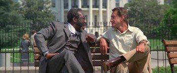 Movie still from “2010: The Year We Make Contact” (1984), directed by Peter Hyams – Two men sitting next to each other on a park bench; Medium shot, Low angle