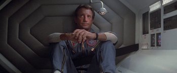 Movie still from “2010: The Year We Make Contact” (1984), directed by Peter Hyams – A man sitting in a chair with his arms crossed; Medium shot, Overhead angle
