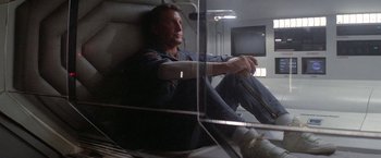 Movie still from “2010: The Year We Make Contact” (1984), directed by Peter Hyams – A man sitting on a chair in a room; Medium shot, Low angle