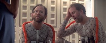 Movie still from “2010: The Year We Make Contact” (1984), directed by Peter Hyams – Two men in body suits sitting next to each other; Medium shot, Low angle