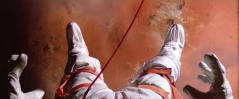 Movie still from “2010: The Year We Make Contact” (1984), directed by Peter Hyams – A person in a spacesuit hanging from a rope; Wide shot, Overhead angle
