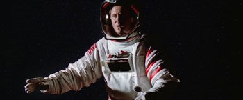 Movie still from “2010: The Year We Make Contact” (1984), directed by Peter Hyams – A man in a spacesuit standing in front of a star filled sky; Medium shot, Low angle