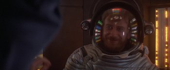 Movie still from “2010: The Year We Make Contact” (1984), directed by Peter Hyams – A man in a spacesuit is smiling for the camera; Close Up shot, Over the shoulder angle