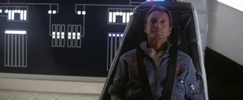 Movie still from “2010: The Year We Make Contact” (1984), directed by Peter Hyams – A man sitting in a chair in front of a building; Close Up shot, Low angle