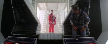 Movie still from “2010: The Year We Make Contact” (1984), directed by Peter Hyams – A man in a red suit standing on a staircase; Wide shot, High angle