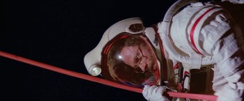 Movie still from “2010: The Year We Make Contact” (1984), directed by Peter Hyams – A man in a spacesuit is holding a red stick; Medium shot, Overhead angle