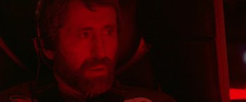Movie still from “2010: The Year We Make Contact” (1984), directed by Peter Hyams – A person with a beard in a dark room; Close Up shot, Low angle
