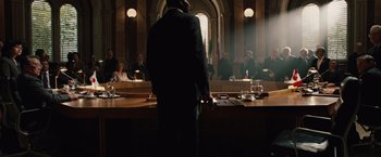 Movie still from “2012” (2009), directed by Roland Emmerich – A man standing in front of a group of people in a court room; Wide shot, Low angle