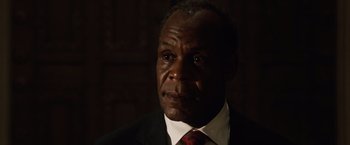 Movie still from “2012” (2009), directed by Roland Emmerich – A person wearing a suit and tie; Close Up shot, Low angle