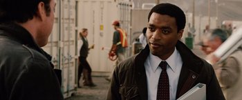 Movie still from “2012” (2009), directed by Roland Emmerich – A man wearing a suit and a tie; Close Up shot, Over the shoulder angle