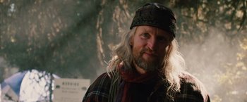 Movie still from “2012” (2009), directed by Roland Emmerich – A man with long white hair wearing a hat; Close Up shot, Low angle