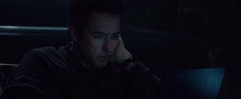 Movie still from “2012” (2009), directed by Roland Emmerich – A person sitting in a dark room; Close Up shot, High angle