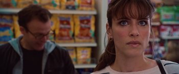 Movie still from “2012” (2009), directed by Roland Emmerich – A woman's face in front of a shelf of potato chips; Close Up shot, Over the shoulder angle