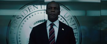 Movie still from “2012” (2009), directed by Roland Emmerich – A man in a suit and tie in front of a seal; Close Up shot, Low angle