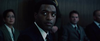 Movie still from “2012” (2009), directed by Roland Emmerich – A man in a suit and tie; Close Up shot, Over the shoulder angle