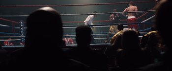 Movie still from “2012” (2009), directed by Roland Emmerich – A boxing ring filled with people watching a fight; Wide shot, High angle