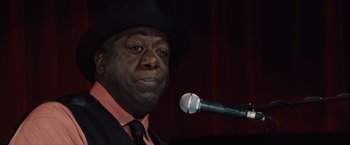 Movie still from “2012” (2009), directed by Roland Emmerich – A person holding a microphone; Close Up shot, Low angle