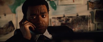 Movie still from “2012” (2009), directed by Roland Emmerich – A person talking on a cell phone; Close Up shot, Over the shoulder angle