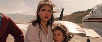 Movie still from “2012” (2009), directed by Roland Emmerich – A woman and a boy standing next to a plane; Close Up shot, Low angle