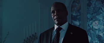 Movie still from “2012” (2009), directed by Roland Emmerich – A man in a suit and tie standing in front of a window; Close Up shot, Low angle